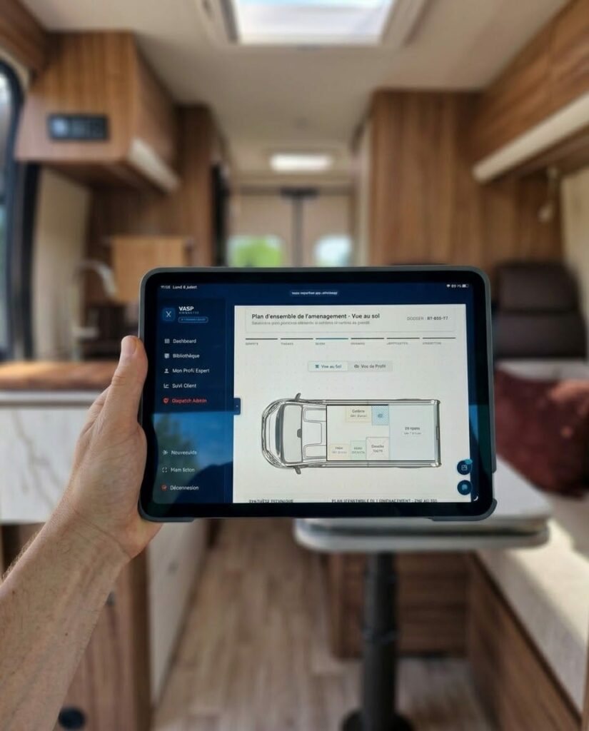 Tablette affichant le logiciel VASP Expertise avec un plan d’aménagement de van, tenue à l’intérieur d’un véhicule de loisirs aménagé.