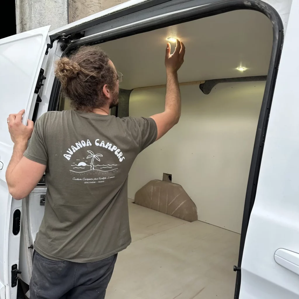 Artisan Avanoa Campers installant l'éclairage LED du plafond d'un van, exposant au Provence Van Week-End