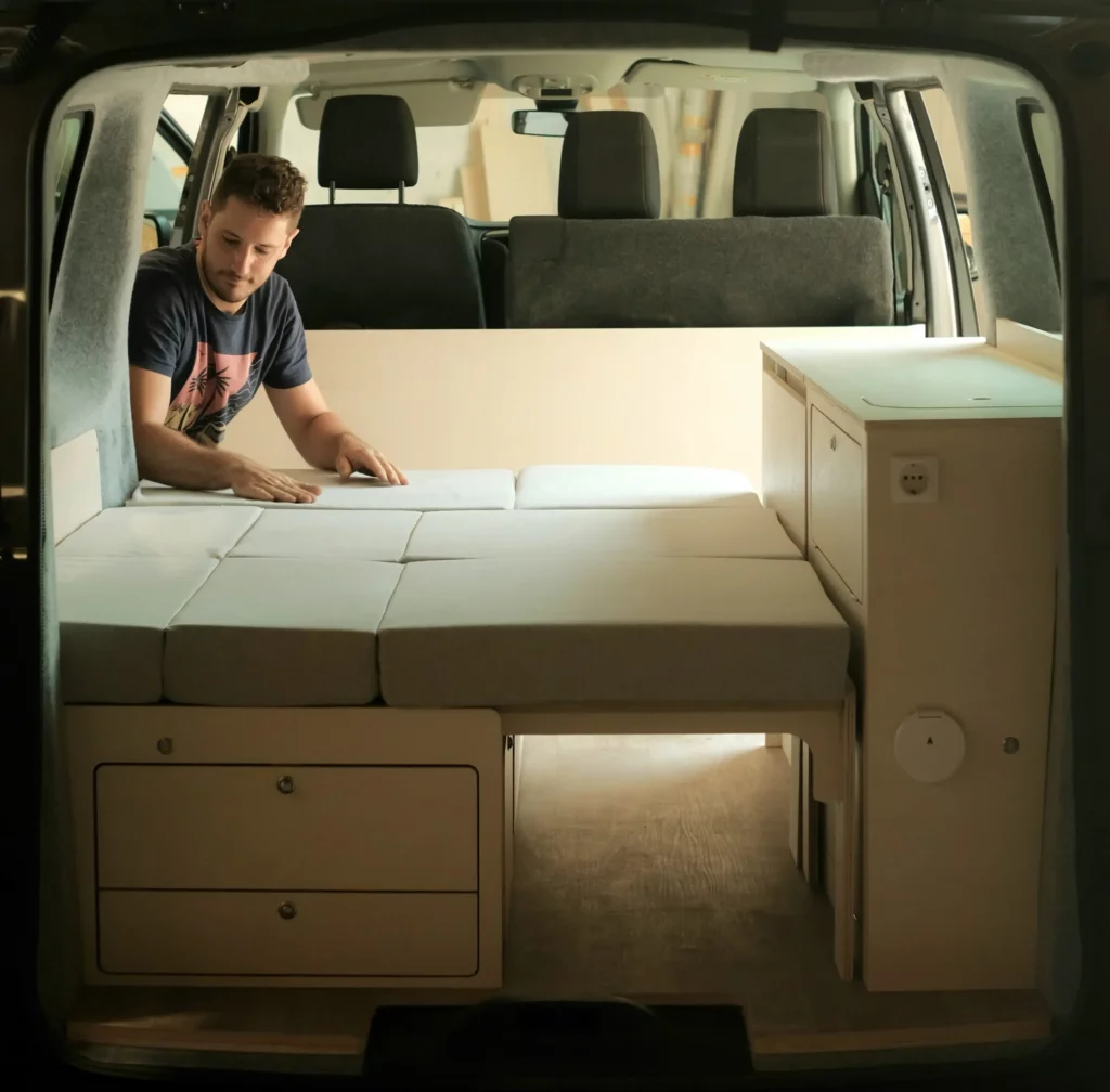 Artisan Avanoa Campers assemblant la plateforme de couchage d'un van, exposant au Provence Van Week-End