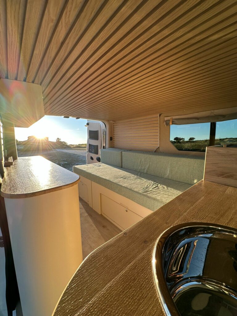 Intérieur d'un van aménagé par 6govan, exposant au Provence Van Week-End, avec plan de travail bois, banquette verte et évier